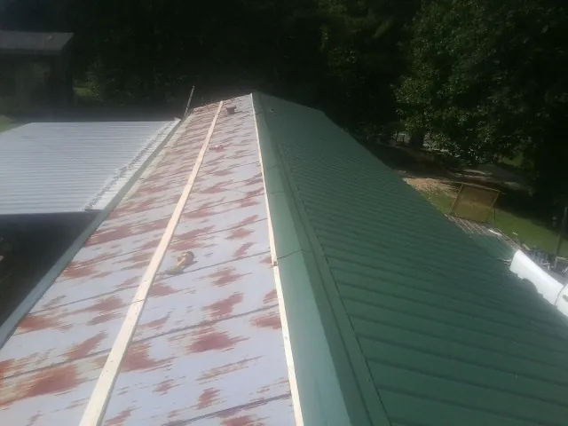 Old rusted panels beside newly installed green metal roofing — Wind Damage Roof Repair by Roofing Brothers in North Arlington