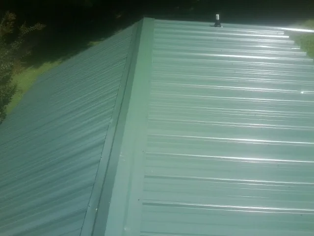 New green metal panels meeting at the ridge of a roof — Flat Roof Repair work by our crew in North Arlington