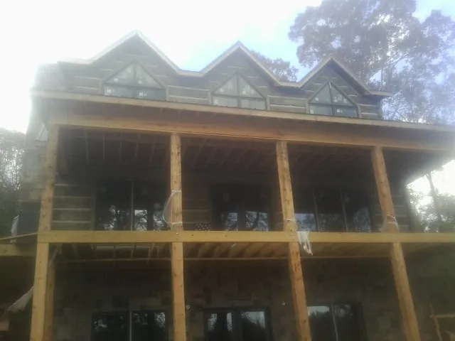 Dormers and porch framing on a large log home under construction — Roof Coating work by our crew in North Arlington