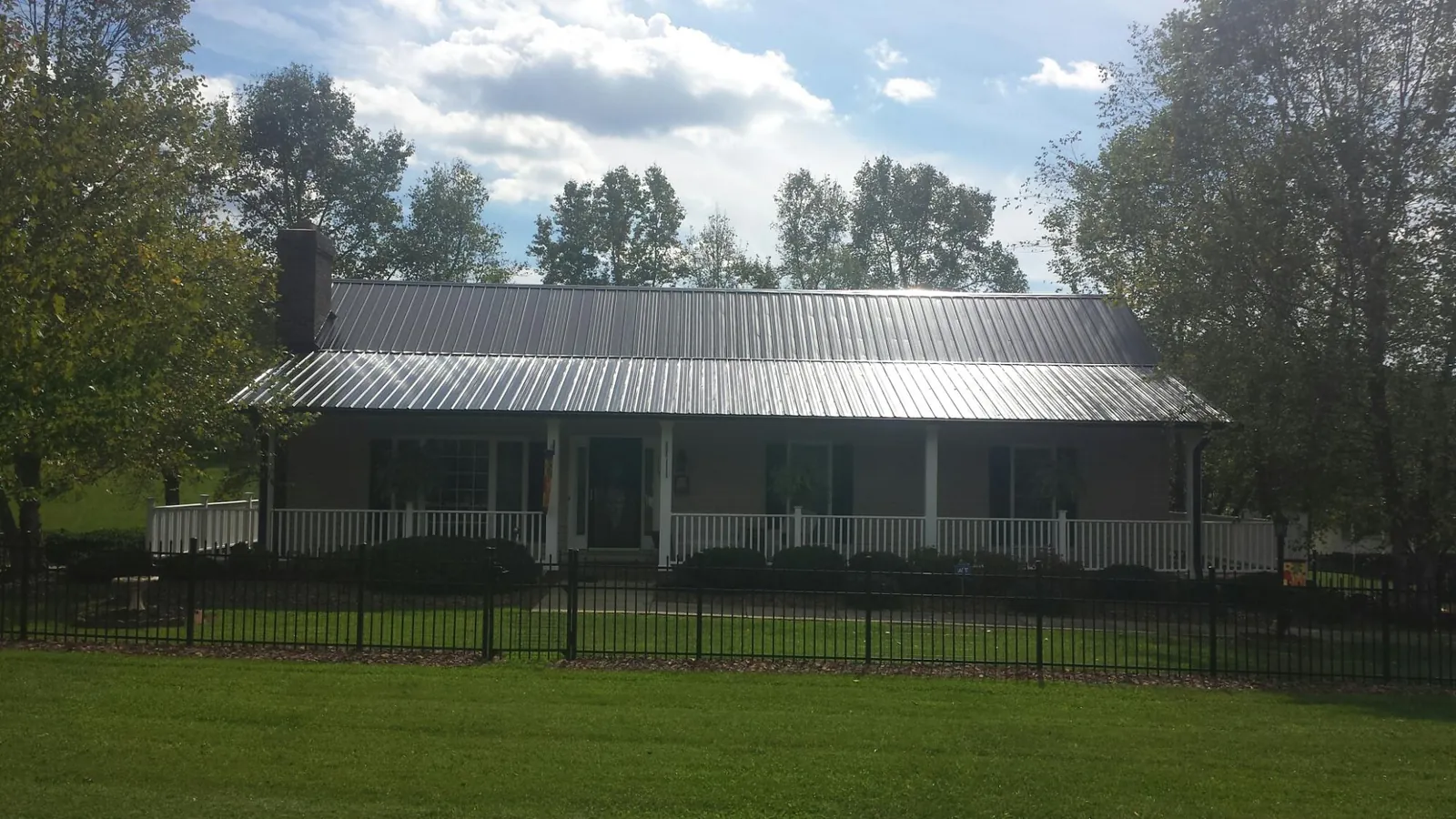 Gray metal roof on a brick ranch with a full width front porch — Gutter Guard Installation work by our crew in North Arlington