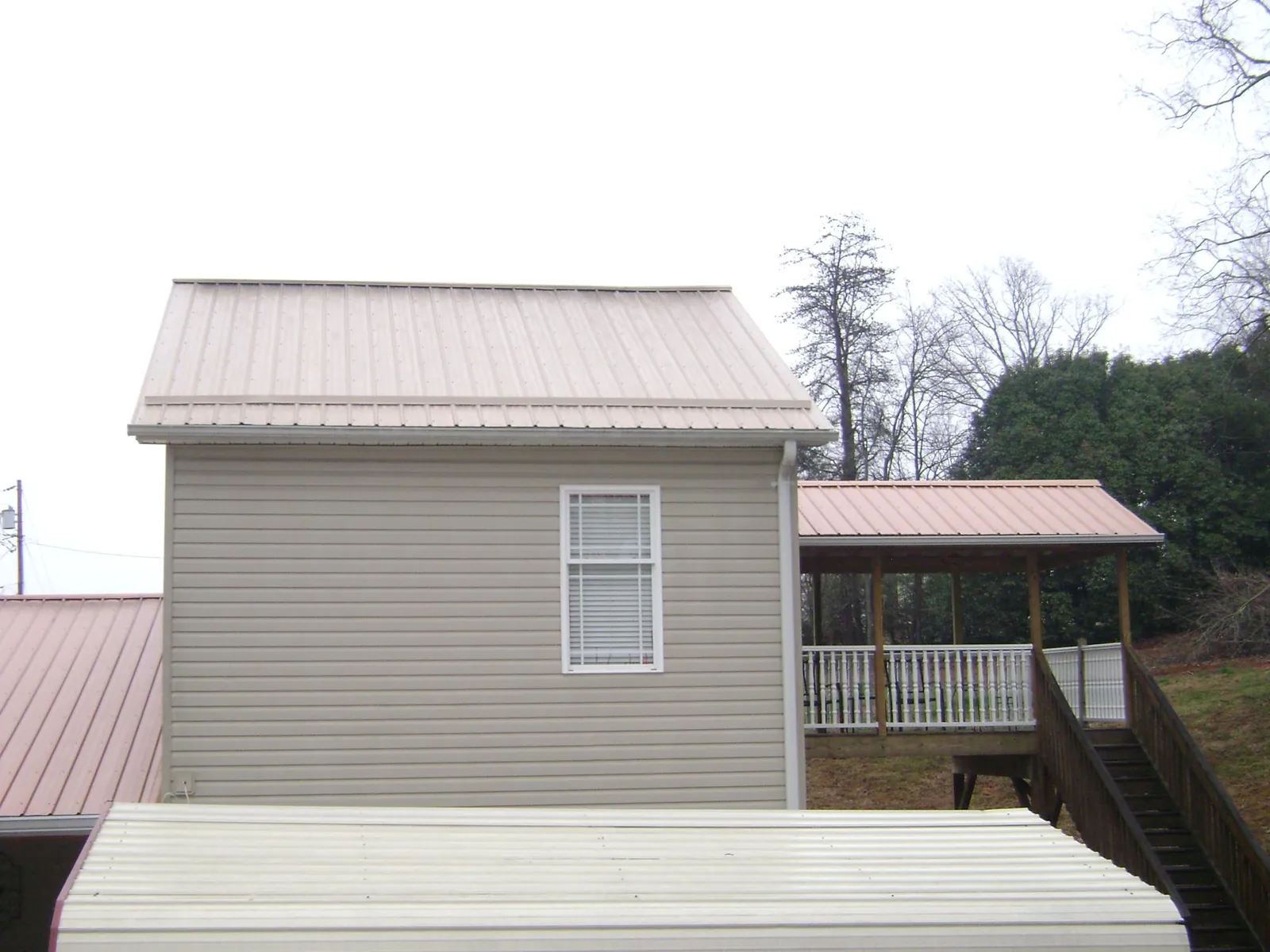 Tan metal roofs on a two story addition and attached porch, from a Roof Replacement job in North Arlington