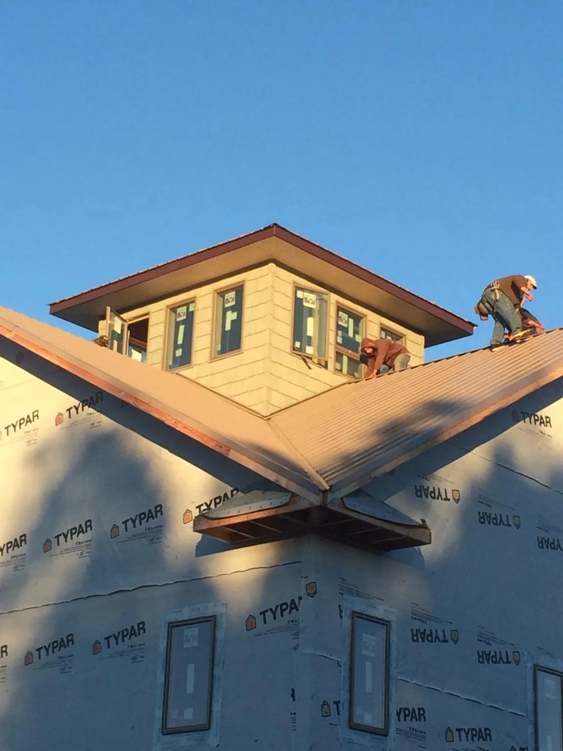 Roofers working around a rooftop cupola on a new metal roof at sunset — Roof Waterproofing in North Arlington by Roofing Brothers
